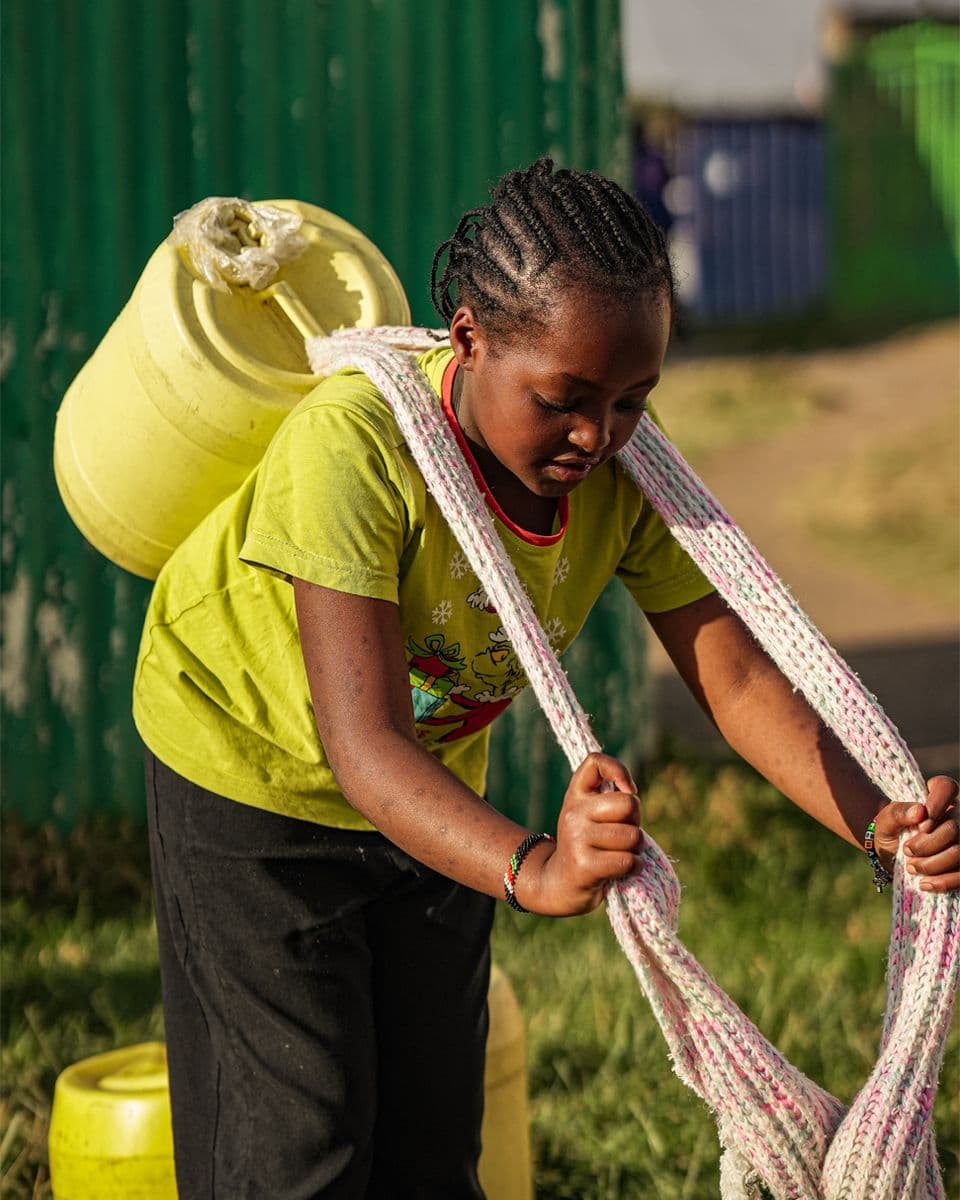 A girl carrying a water container, Kenya
